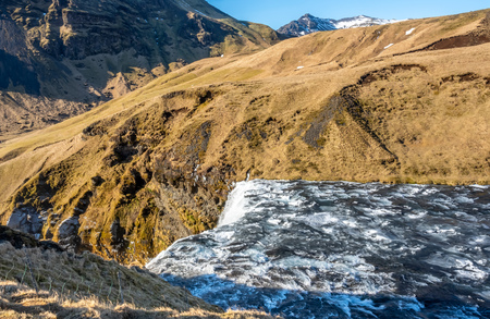 Streaming river at top of Skogafoss waterfall with snow and ice in winter season in Icelandの写真素材