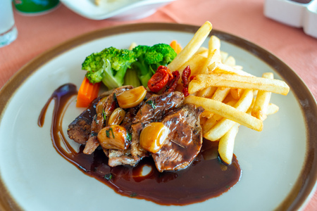 Pork steak with red wine sauce serve with potato fried and carrot, broccoli and mushroom on round dish in European restaurantの写真素材