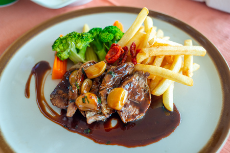 Pork steak with red wine sauce serve with potato fried and carrot, broccoli and mushroom on round dish in European restaurantの写真素材