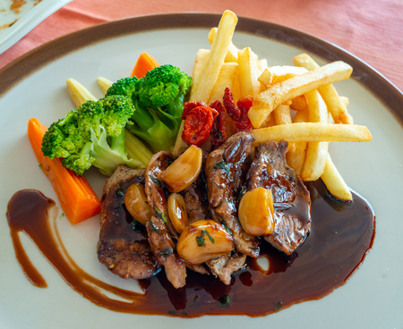 Pork steak with red wine sauce serve with potato fried and carrot, broccoli and mushroom on round dish in European restaurantの写真素材