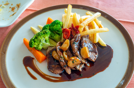 Pork steak with red wine sauce serve with potato fried and carrot, broccoli and mushroom on round dish in European restaurantの写真素材