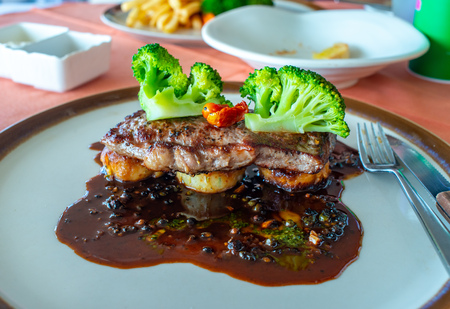 Sirloin beef steak with red wine sauce served with potato and broccoli on white round dish in European restaurantの写真素材