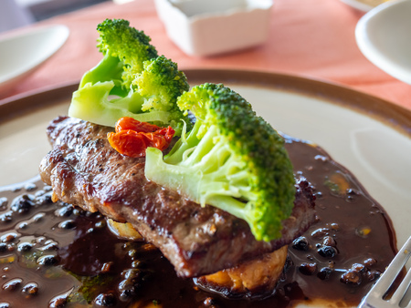 Sirloin beef steak with red wine sauce served with potato and broccoli on white round dish in European restaurant, selective focusの写真素材