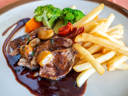 Pork steak with red wine sauce serve with potato fried and carrot, broccoli and mushroom on round dish in European restaurant, selective focusの写真素材