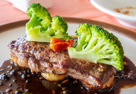 Sirloin beef steak with red wine sauce served with potato and broccoli on white round dish in European restaurant, selective focusの写真素材
