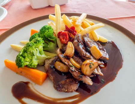 Pork steak with red wine sauce serve with potato fried and carrot, broccoli and mushroom on round dish in European restaurant, selective focusの写真素材