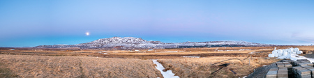 Mountain, field in twilight evening sky with full moon night light in winter season in Icelandの写真素材