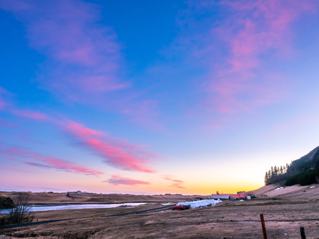 Natural view of mountain and field in outdoor farm under twilight evening sky in Iceland during winter seasonの写真素材