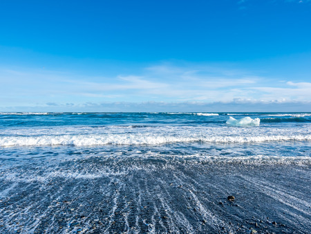 Large ice pieces with ocean wave in winter season at black sand diamond beach in Icelandの写真素材