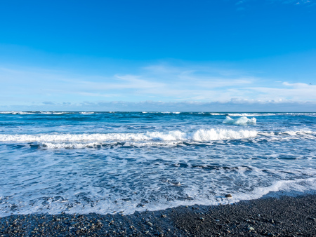 Large ice pieces with ocean wave in winter season at black sand diamond beach in Icelandの写真素材
