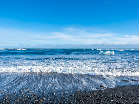 Large ice pieces with ocean wave in winter season at black sand diamond beach in Icelandの写真素材