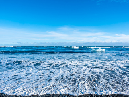 Large ice pieces with ocean wave in winter season at black sand diamond beach in Icelandの写真素材