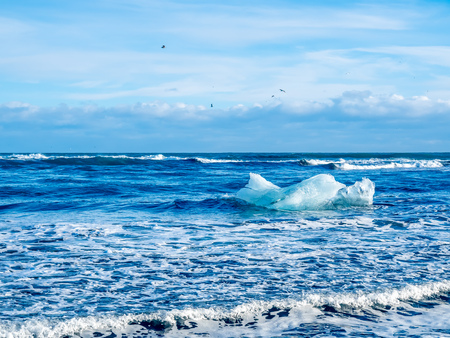 Large ice pieces with ocean wave in winter season at black sand diamond beach in Icelandの写真素材
