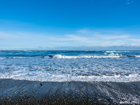 Black sand diamond beach with wave and snow mountains in winter season in Icelandの写真素材