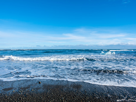 Black sand diamond beach with wave and snow mountains in winter season in Icelandの写真素材