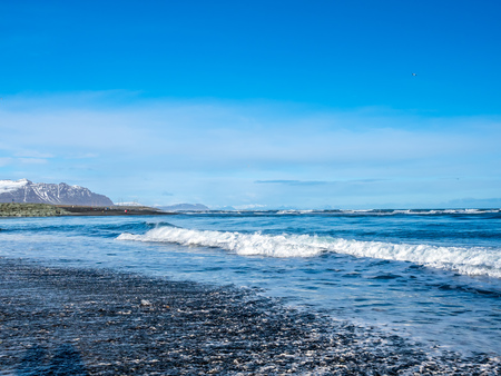 Black sand diamond beach with wave and snow mountains in winter season in Icelandの写真素材