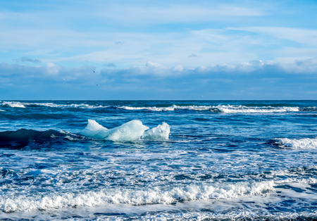 Large ice pieces with ocean wave in winter season at black sand diamond beach in Icelandの写真素材