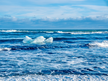 Large ice pieces with ocean wave in winter season at black sand diamond beach in Icelandの写真素材