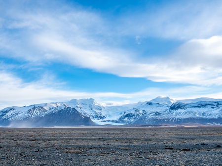 Viewpoint to Hvannadalshnukur peak, with wide plain of black volcanic sand marbled with creeks of run-off from the Skeioararjokull glacierの写真素材