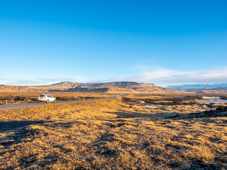 Natural scene with morning mist, field, mountains and cloudy blue sky in rural area in Icelandの写真素材