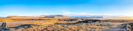 Panorama view of natural scene with morning mist, field, mountains and cloudy blue sky in rural area in Icelandの写真素材