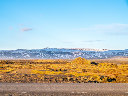 Natural scene with morning mist, field, mountains and cloudy blue sky in rural area in Icelandの写真素材