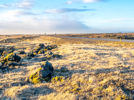 Natural scene with morning mist, field, mountains and cloudy blue sky in rural area in Icelandの写真素材