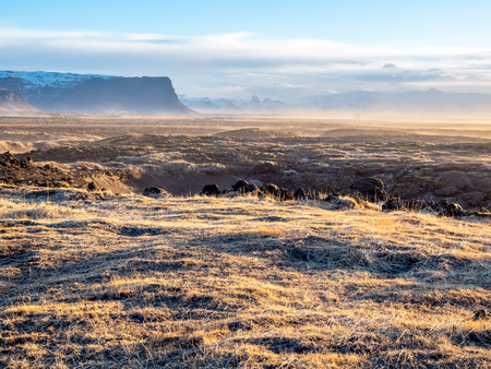 Natural scene with morning mist, field, mountains and cloudy blue sky in rural area in Icelandの写真素材