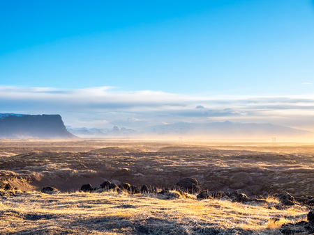 Natural scene with morning mist, field, mountains and cloudy blue sky in rural area in Icelandの写真素材