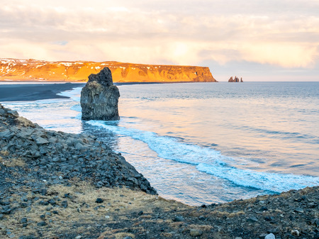 Arnardrangur, known as Eagle rock, at coastline near Dyrholaey arch surrounding with heavy wave and rocky mountains at south of Icelandの写真素材