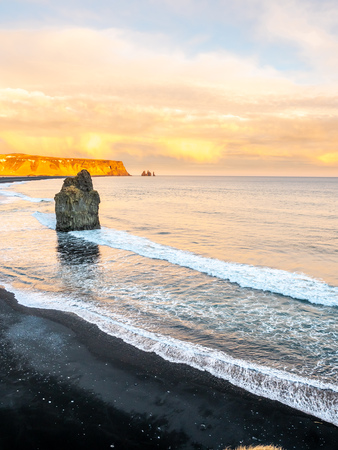 Arnardrangur, known as Eagle rock, at coastline near Dyrholaey arch surrounding with heavy wave and rocky mountains at south of Icelandの写真素材
