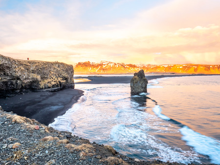 Arnardrangur, known as Eagle rock, at coastline near Dyrholaey arch surrounding with heavy wave and rocky mountains at south of Icelandの写真素材