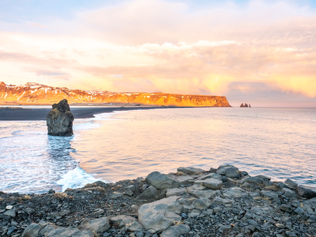 Arnardrangur, known as Eagle rock, at coastline near Dyrholaey arch surrounding with heavy wave and rocky mountains at south of Icelandの写真素材