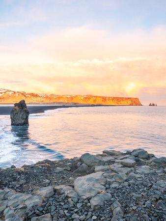 Arnardrangur, known as Eagle rock, at coastline near Dyrholaey arch surrounding with heavy wave and rocky mountains at south of Icelandの写真素材