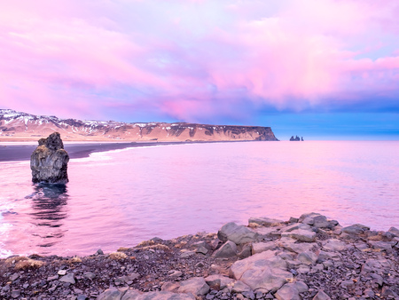 Arnardrangur, known as Eagle rock, at coastline near Dyrholaey arch surrounding with heavy wave and rocky mountains at south of Icelandの写真素材