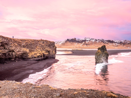 Arnardrangur, known as Eagle rock, at coastline near Dyrholaey arch surrounding with heavy wave and rocky mountains at south of Icelandの写真素材