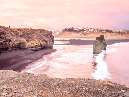 Arnardrangur, known as Eagle rock, at coastline near Dyrholaey arch surrounding with heavy wave and rocky mountains at south of Icelandの写真素材