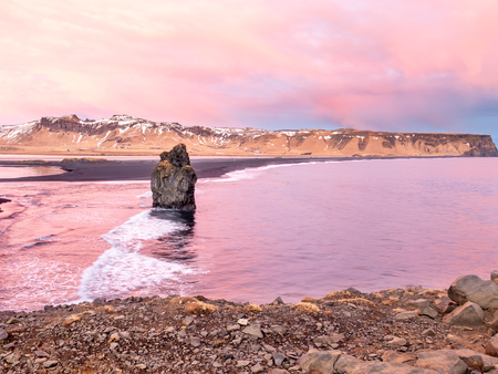 Arnardrangur, known as Eagle rock, at coastline near Dyrholaey arch surrounding with heavy wave and rocky mountains at south of Icelandの写真素材