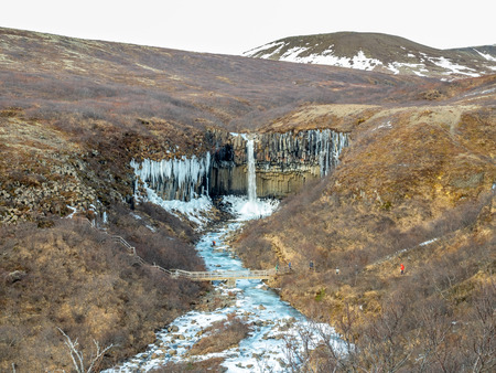 Svartifoss waterfall, one of unique landmark in Iceland, located in Vatnajokull national park, like oasis in black larva sand plain, water freeze in winter seasonの写真素材