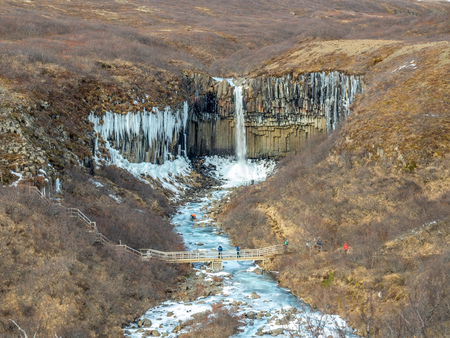 Svartifoss waterfall, one of unique landmark in Iceland, located in Vatnajokull national park, like oasis in black larva sand plain, water freeze in winter seasonの写真素材