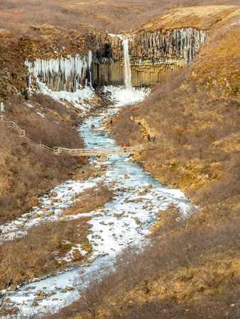 Svartifoss waterfall, one of unique landmark in Iceland, located in Vatnajokull national park, like oasis in black larva sand plain, water freeze in winter seasonの写真素材