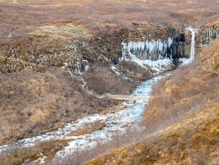Svartifoss waterfall, one of unique landmark in Iceland, located in Vatnajokull national park, like oasis in black larva sand plain, water freeze in winter seasonの写真素材