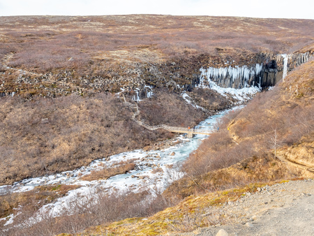 Svartifoss waterfall, one of unique landmark in Iceland, located in Vatnajokull national park, like oasis in black larva sand plain, water freeze in winter seasonの写真素材