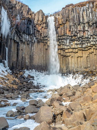 Svartifoss waterfall, one of unique landmark in Iceland, located in Vatnajokull national park, like oasis in black larva sand plain, water freeze in winter seasonの写真素材