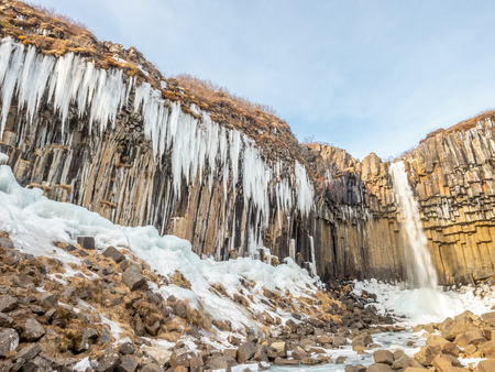 Svartifoss waterfall, one of unique landmark in Iceland, located in Vatnajokull national park, like oasis in black larva sand plain, water freeze in winter seasonの写真素材