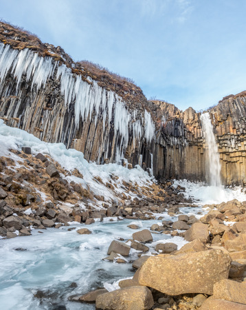 Svartifoss waterfall, one of unique landmark in Iceland, located in Vatnajokull national park, like oasis in black larva sand plain, water freeze in winter seasonの写真素材