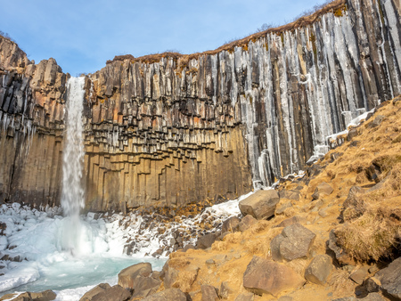 Svartifoss waterfall, one of unique landmark in Iceland, located in Vatnajokull national park, like oasis in black larva sand plain, water freeze in winter seasonの写真素材