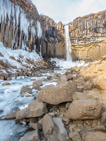 Svartifoss waterfall, one of unique landmark in Iceland, located in Vatnajokull national park, like oasis in black larva sand plain, water freeze in winter seasonの写真素材