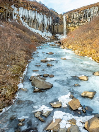 Svartifoss waterfall, one of unique landmark in Iceland, located in Vatnajokull national park, like oasis in black larva sand plain, water freeze in winter seasonの写真素材