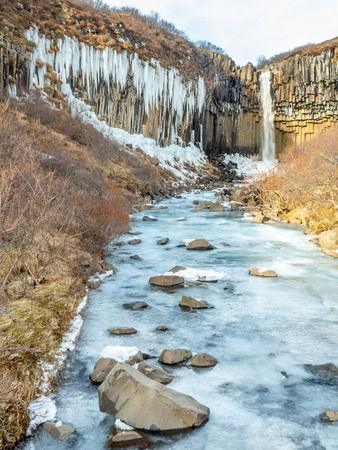 Svartifoss waterfall, one of unique landmark in Iceland, located in Vatnajokull national park, like oasis in black larva sand plain, water freeze in winter seasonの写真素材